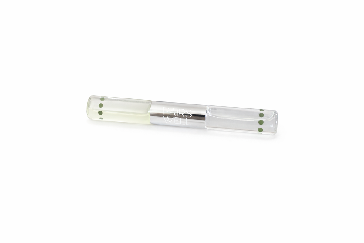 Dual-ended glass bottle with fragrance on one end and clear lip serum on the other end